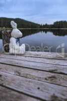 Fluffy toy bunny sitting on a pier