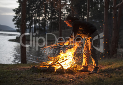 Man lights a fire in the fireplace in nature