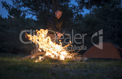 Man lights a fire in the fireplace in nature