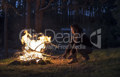 Man lights a fire in the fireplace in nature