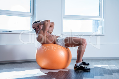 In gym. Bodybuilder doing push-ups on fitness ball