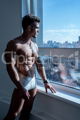 Image of bodybuilder posing standing at window
