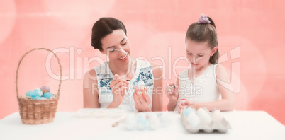 Composite image of mother and daughter painting easter eggs