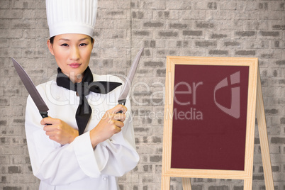 Composite image of confident female cook holding knives in kitchen