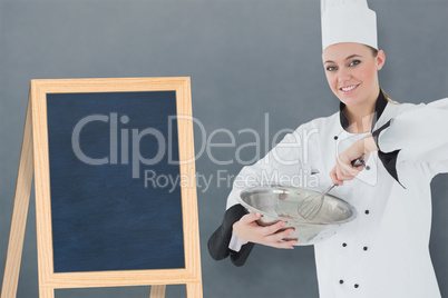 Composite image of happy female chef holding wire whisk and mixing bowl