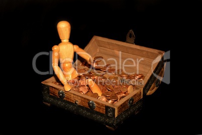 Holzfigur sitzt in Holzkiste mit Geld