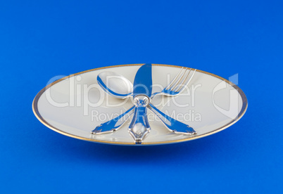 Close up Spoon, Fork and Knife Tied on White dish, on blue table