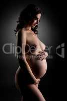 Pregnant woman posing nude and smiling shyly