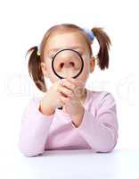 Cute little girl is playing with magnifier