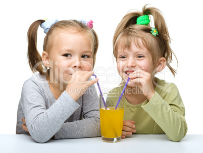 Two Little girls are drinking orange juice