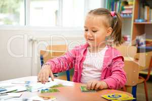 Cute little girl is playing with educational cards