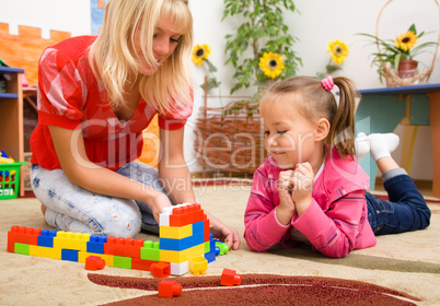 Teacher and child are playing with bricks