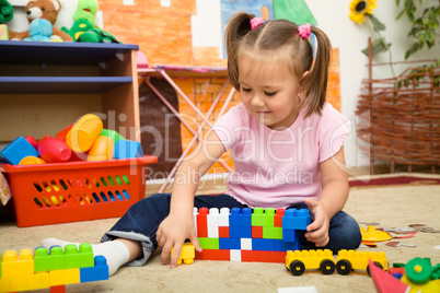 Little girl is playing with building bricks