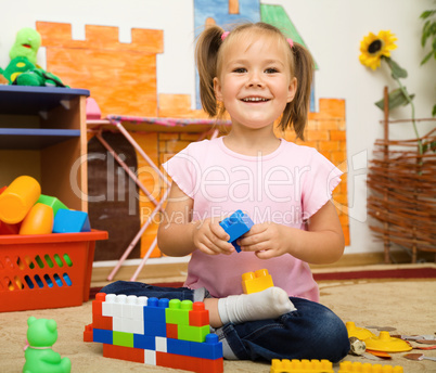 Little girl is playing with toys in preschool