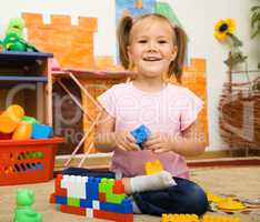Little girl is playing with toys in preschool