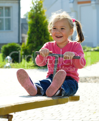 Cute little girl is swinging on see-saw