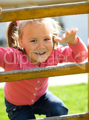 Cute little girl is climbing up on ladder