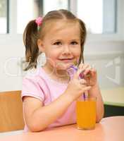 Little girl is drinking orange juice