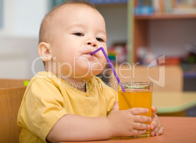 Little boy is drinking orange juice