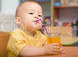 Little boy is drinking orange juice