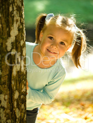 Little girl is playing in autumn park