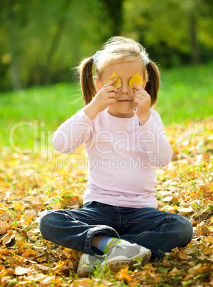 Little girl is playing in autumn park