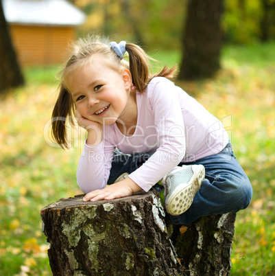 Little girl is playing in autumn park