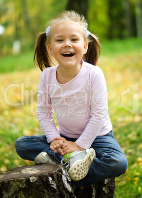 Little girl is playing in autumn park