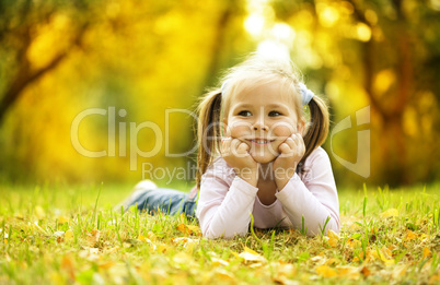 Cute little girl is playing with leaves in park