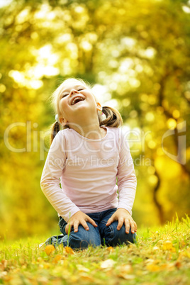 Cute little girl is playing with leaves in park