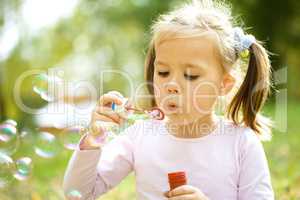 Little girl is blowing a soap bubbles