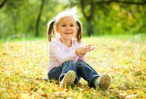 Little girl is sitting on green meadow