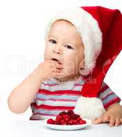 Cute little boy eating berries wearing santa hat