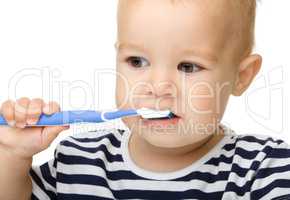 Little boy is cleaning teeth using toothbrush