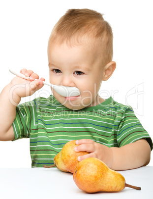 Cute little boy with pears is biting spoon