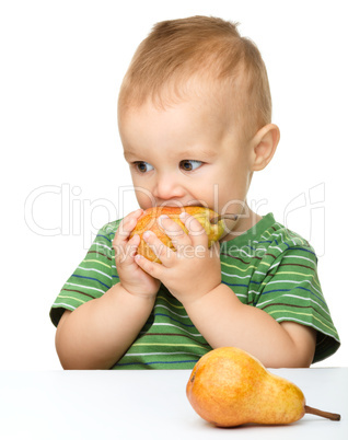 Cute little boy is biting pear