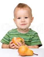 Cute little boy is eating pear