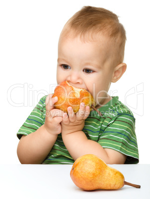 Cute little boy is biting pear