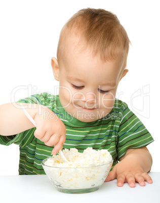 Little boy is eating cottage cheese using spoon
