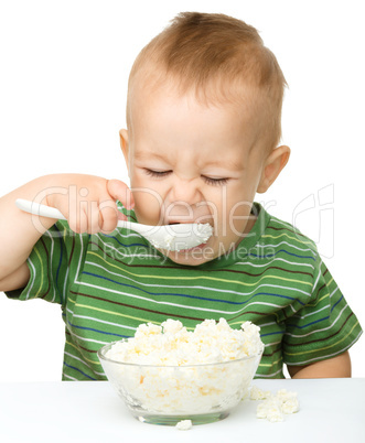 Little boy is eating cottage cheese using spoon