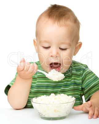 Little boy is eating cottage cheese using spoon