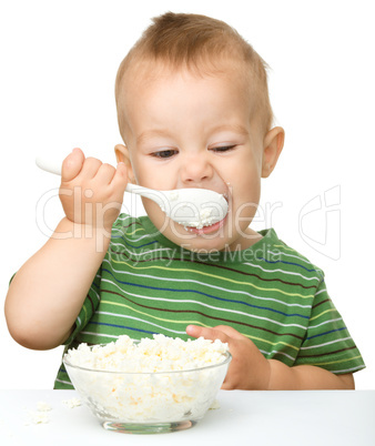 Cute little boy is eating cottage cheese