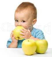 Little boy biting yellow apple