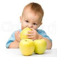 Little boy biting yellow apple