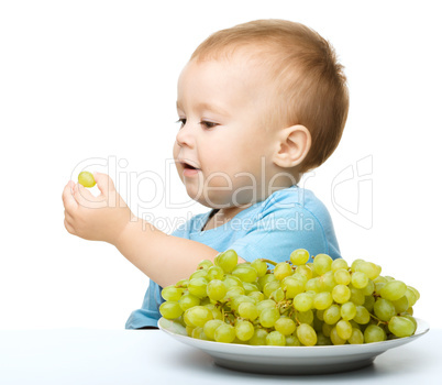 Little boy is eating grapes