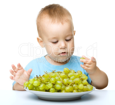 Little boy is eating grapes