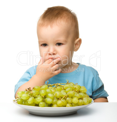Little boy is eating grapes