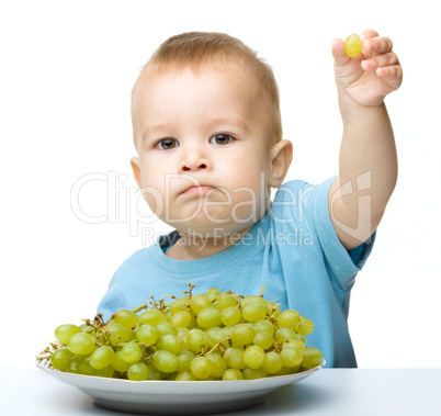 Little boy is eating grapes