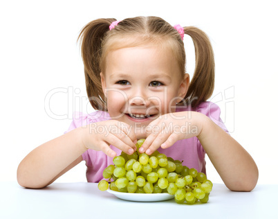 Little girl is eating grapes