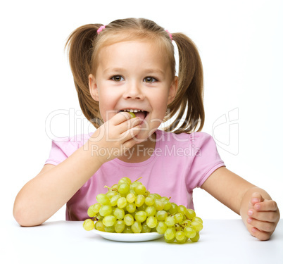 Little girl is eating grapes